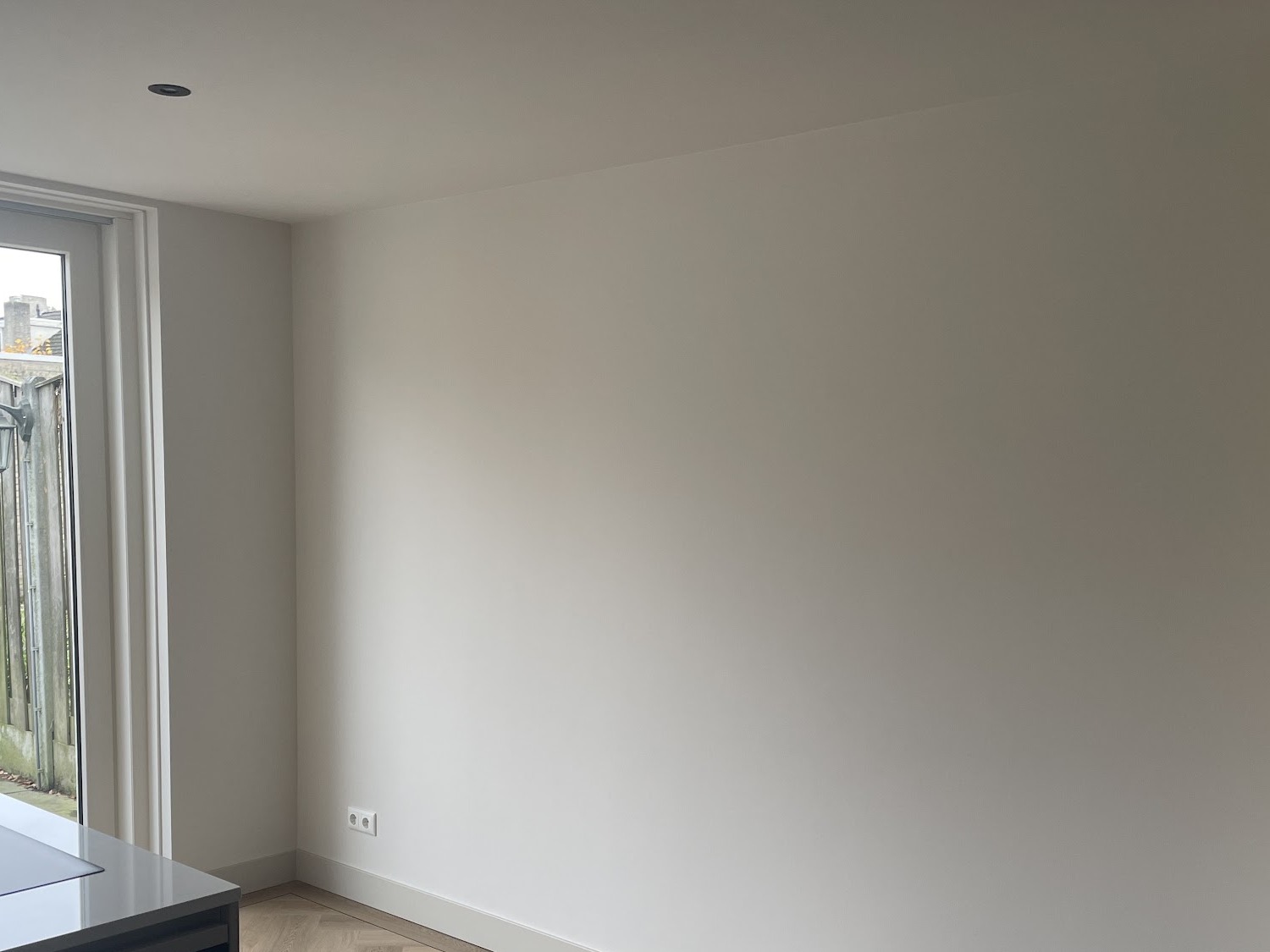 Vers gestucte witte wand en plafond met een raam naar de tuin